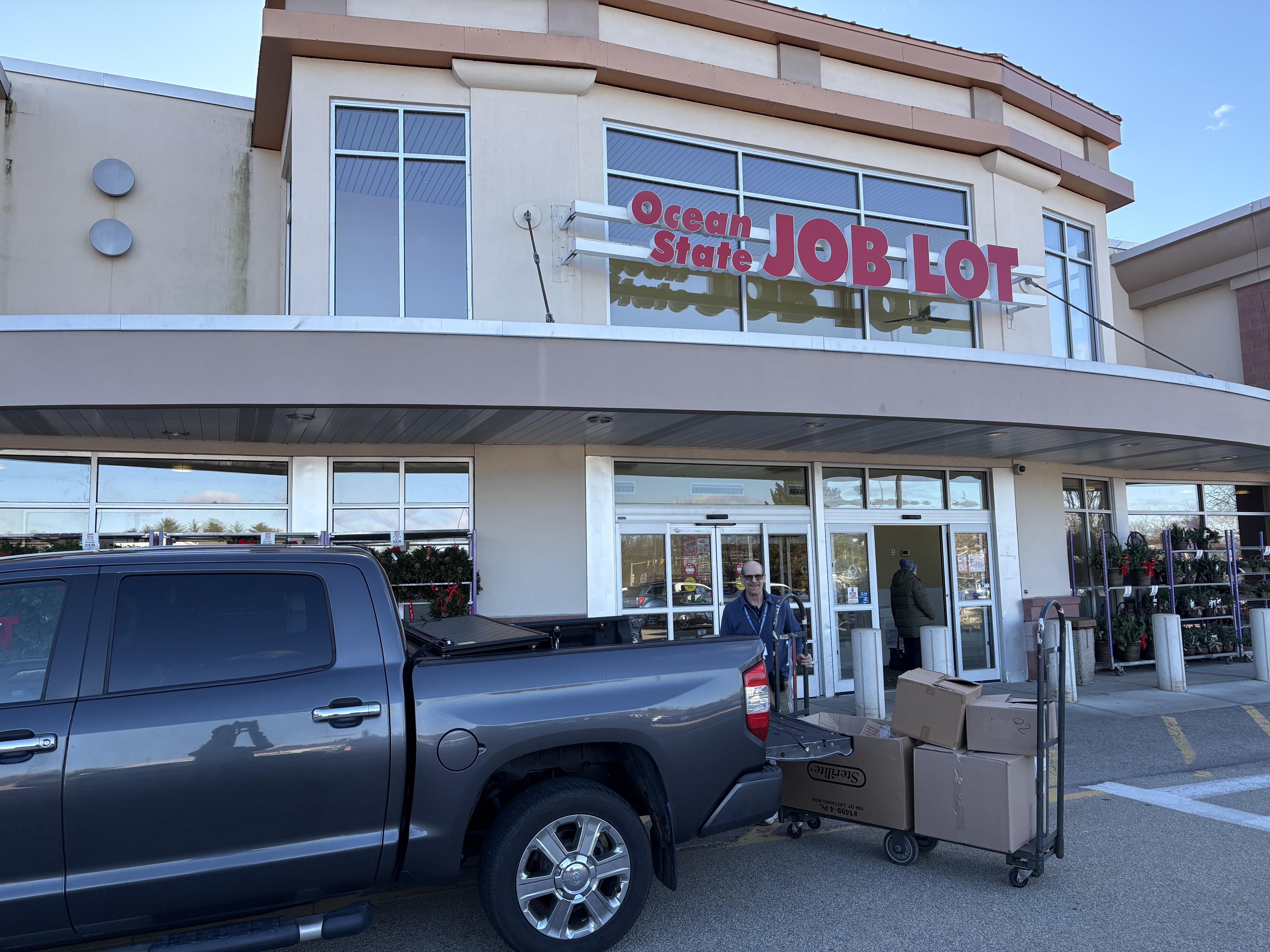 Ocean State Job Lot storefront with a pickup truck and carts of boxed donations near the entrance