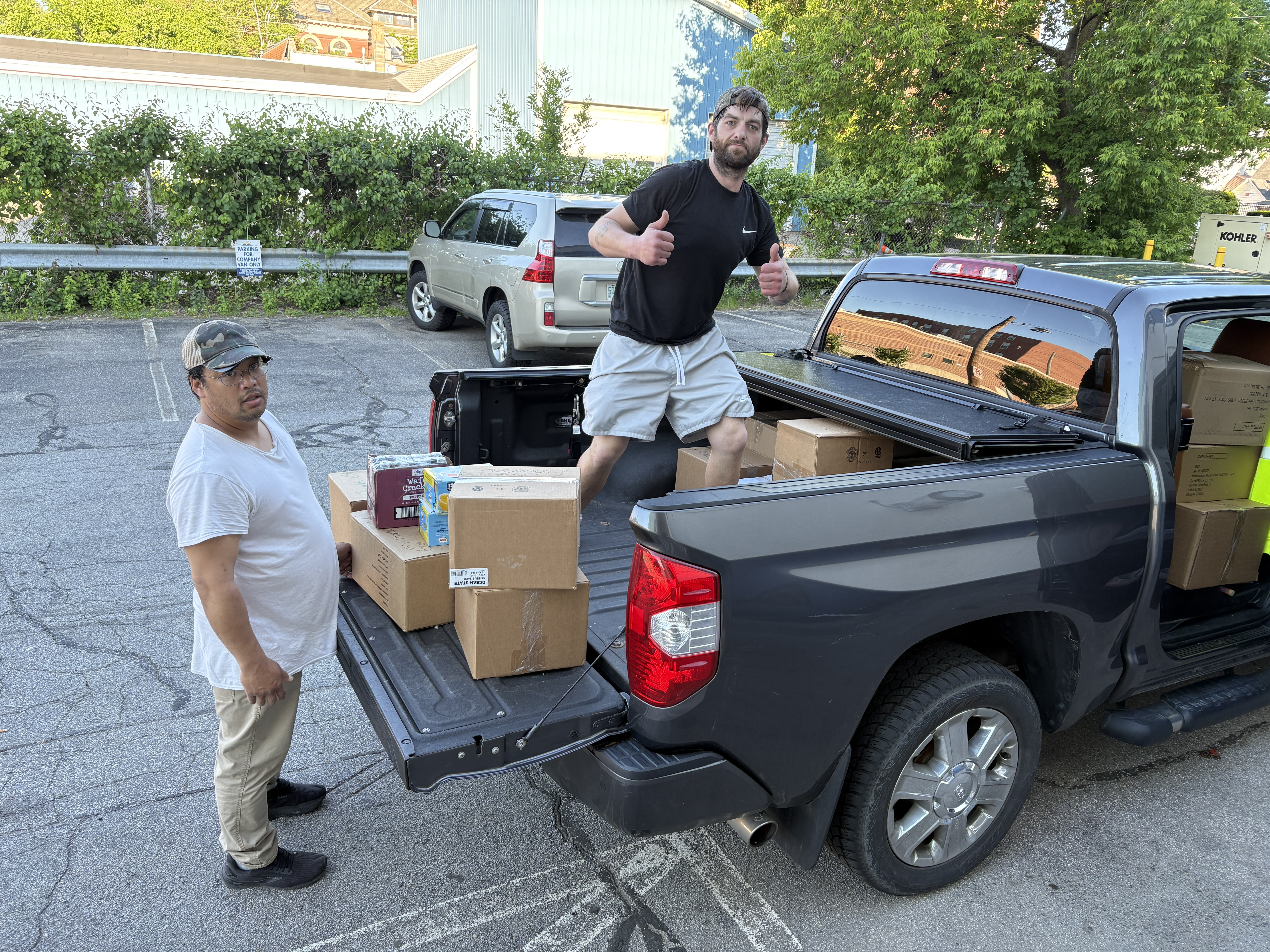 Two people beside a pickup truck loaded with boxes and packaged food
